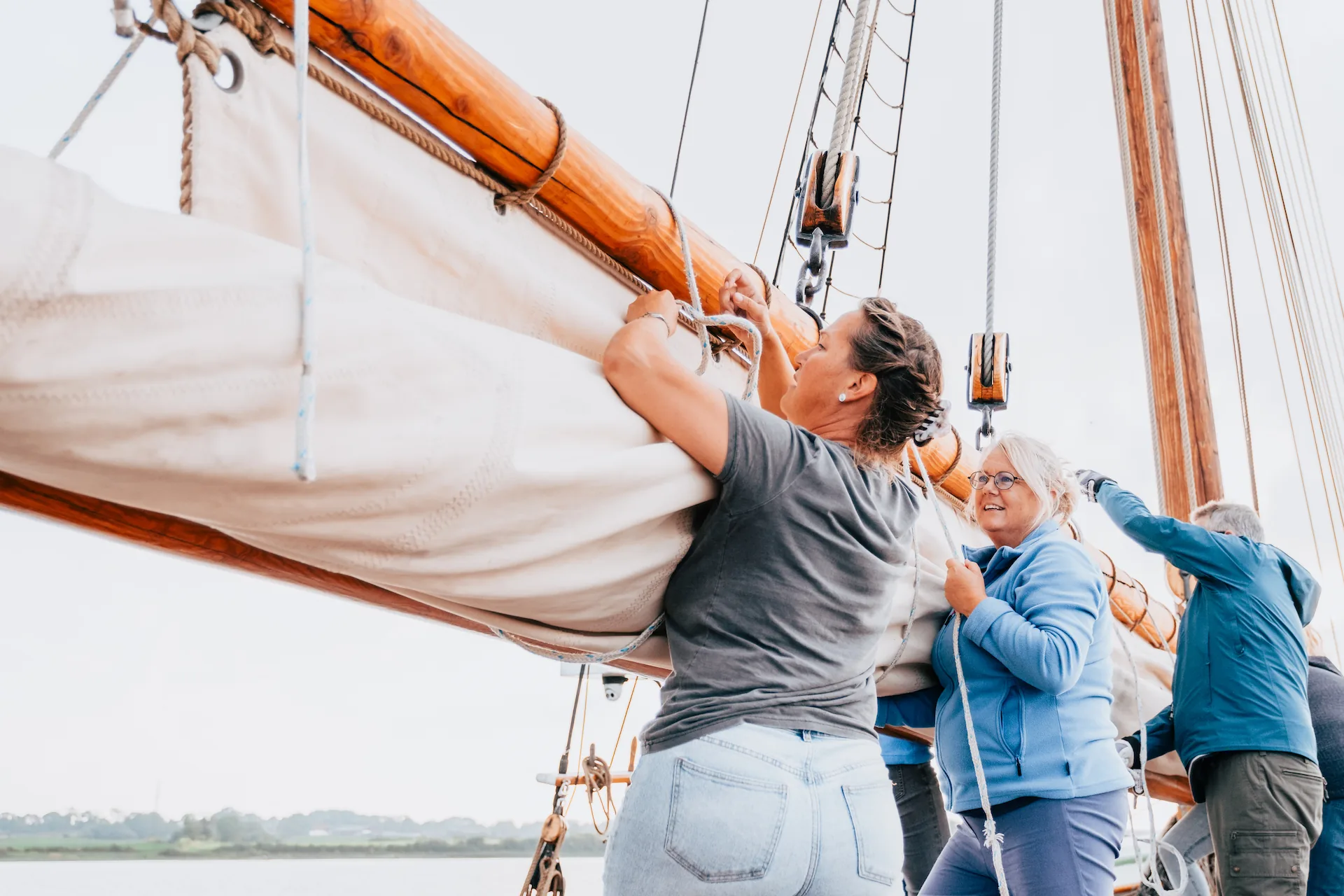 Guests help furl a sail aboard the schooner Aron