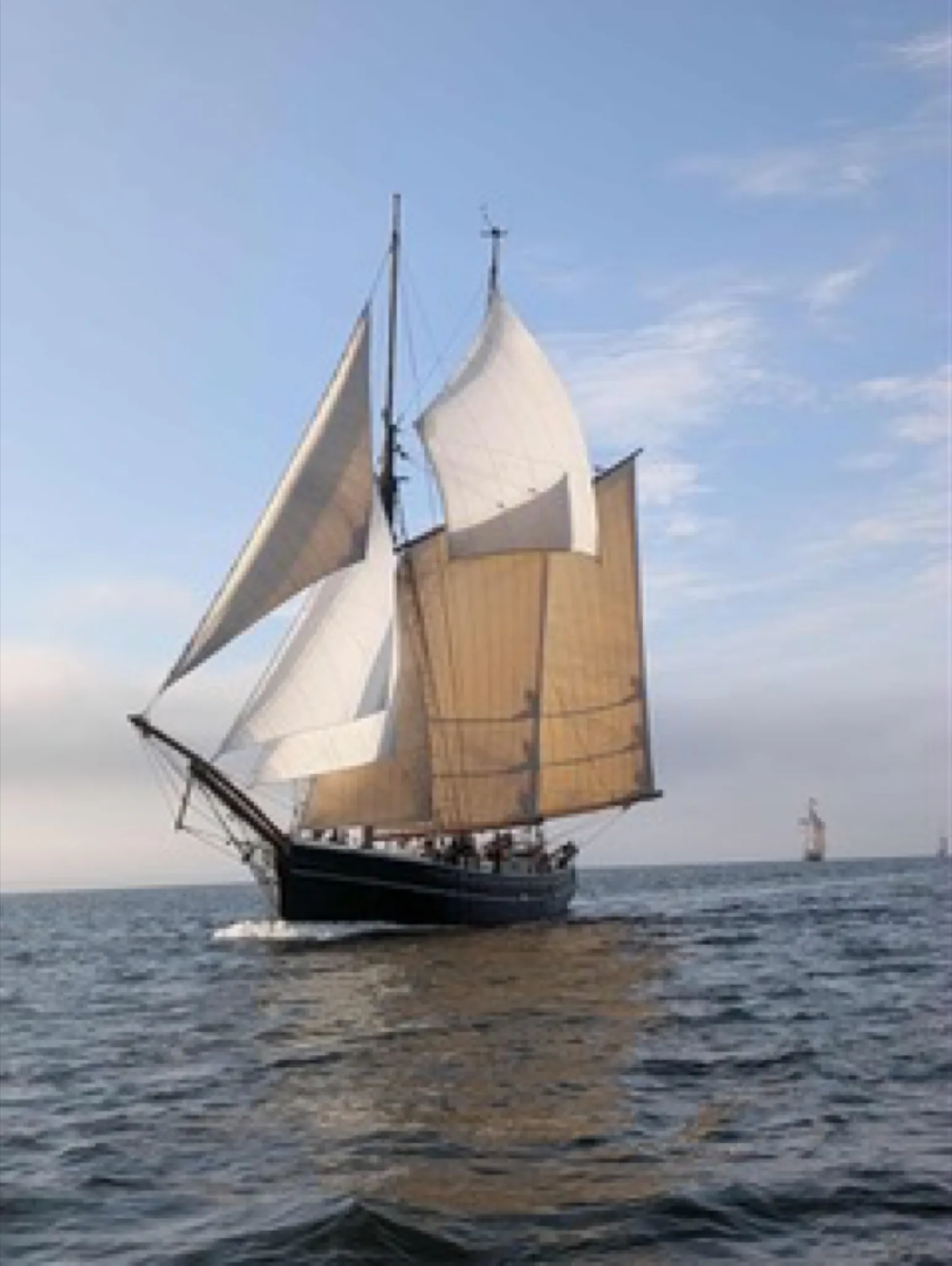 Aron under sail with a tall ship on the horizon