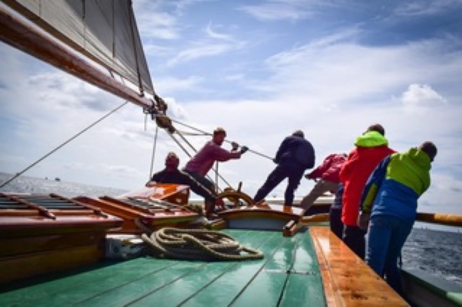 Guests and crew haul a line together on Aron's green deck