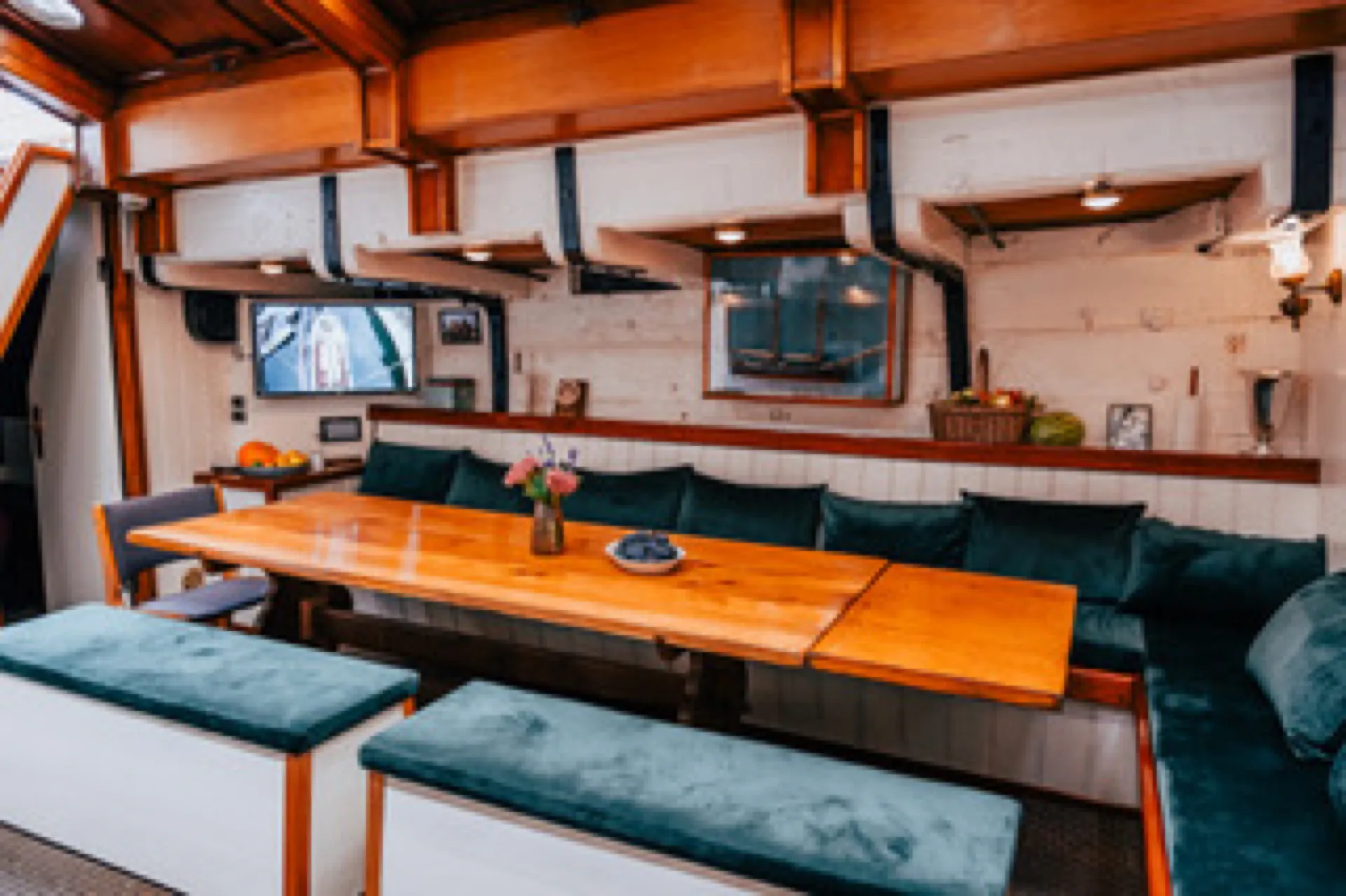 The saloon lounge below deck with green cushions and wooden panelling